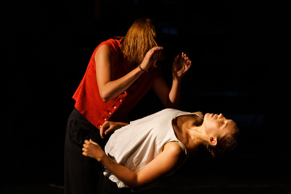 Un danseuse en rouge se penche sur le corps d'une autre danseuse, en blanc.