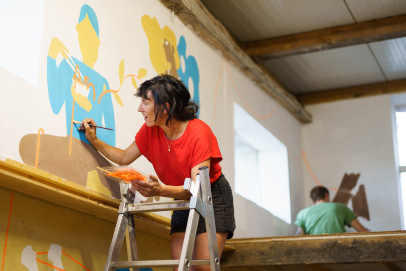 L'illustratrice Aurore Petit, travaillant à la fresque "fil de vie" sur les murs de l'espace Marceline Lartigue à la Bergerie de Soffin.