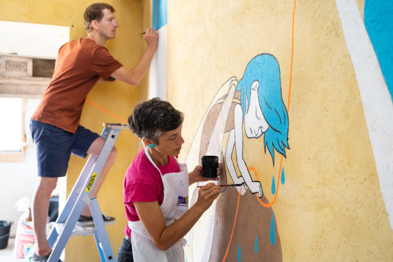 Les illustrateurs Lucie Albon et Matthieu Méron, travaillant à la fresque "fil de vie" sur les murs de l'espace Marceline Lartigue à la Bergerie de Soffin.
