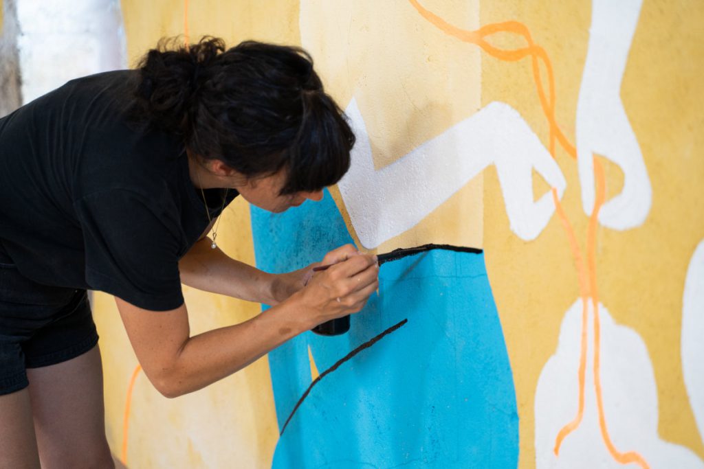 L'illustratrice Aurore Petit en train de travailler à une fresque murale.